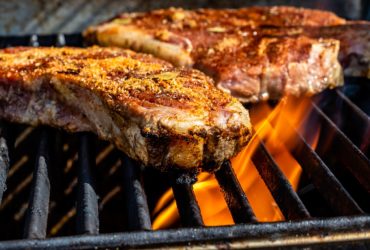 tva-kottbitar-som-ligger-pa-en-brinnande-grill-med-tjocka-grillgaller