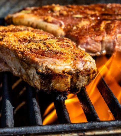 tva-kottbitar-som-ligger-pa-en-brinnande-grill-med-tjocka-grillgaller