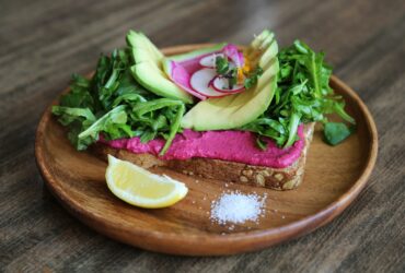 Avokado, limeskiva och bröd på tallrik med salt.