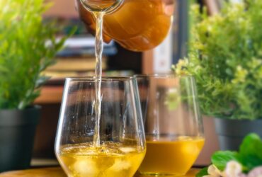 person pouring orange juice on clear drinking glass