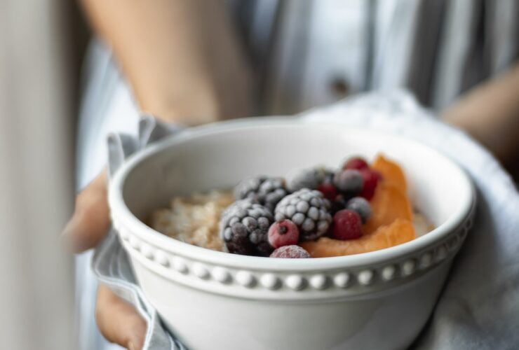 person holding white ceramic bowl with fruits
