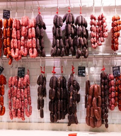 a bunch of sausage hanging from hooks in a kitchen